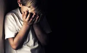 Young boy covering his face in fear